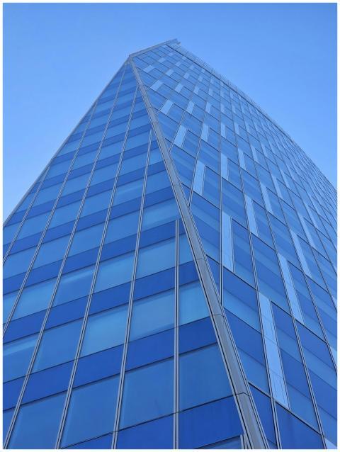 Tall modern skyscraper with blue glass panels agai