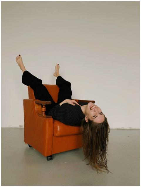 A woman joyfully reclines upside down in a vintage