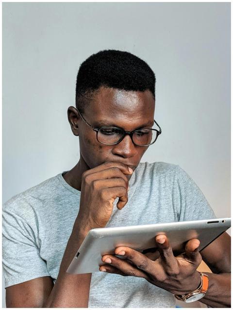 Young man wearing glasses engrossed in using a tab