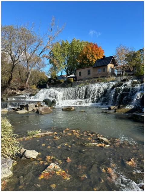 Picturesque waterfall by a rustic house with autum