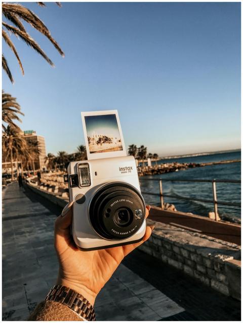 Close-up of a hand holding an Instax camera with s