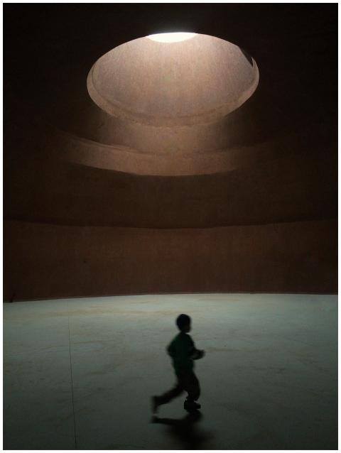 A child runs under a large circular skylight, cast