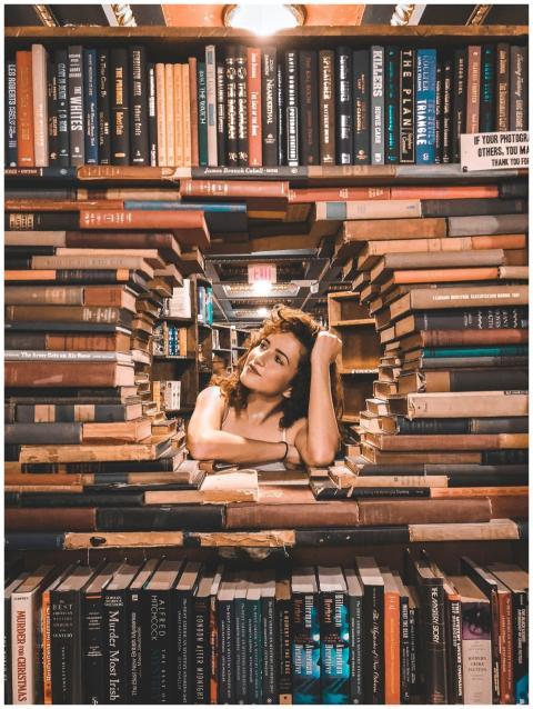 A woman framed by books poses inside a library wit
