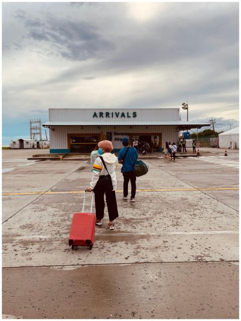 People arriving at Malay Airport under a cloudy sk