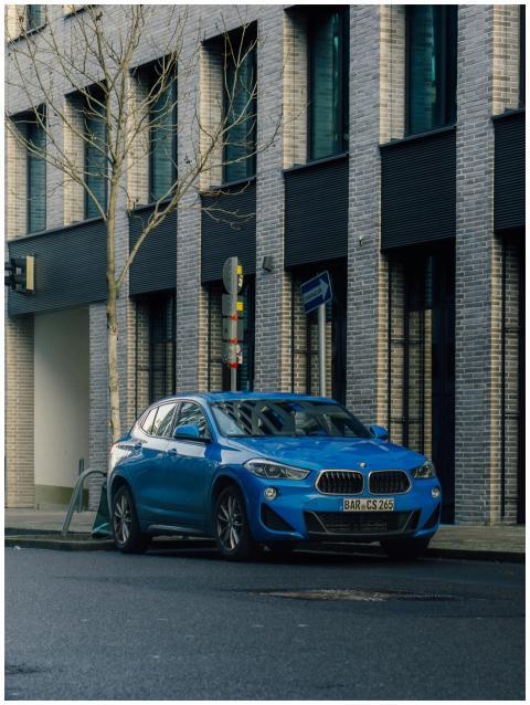 A vibrant blue car parked along an urban street ne