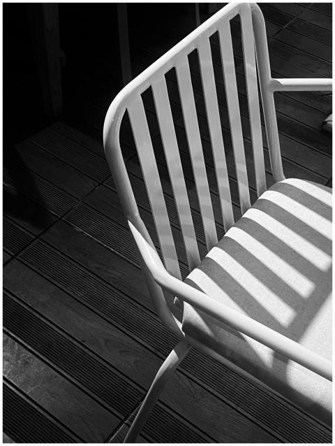 A modern white chair casting shadows outdoors on a
