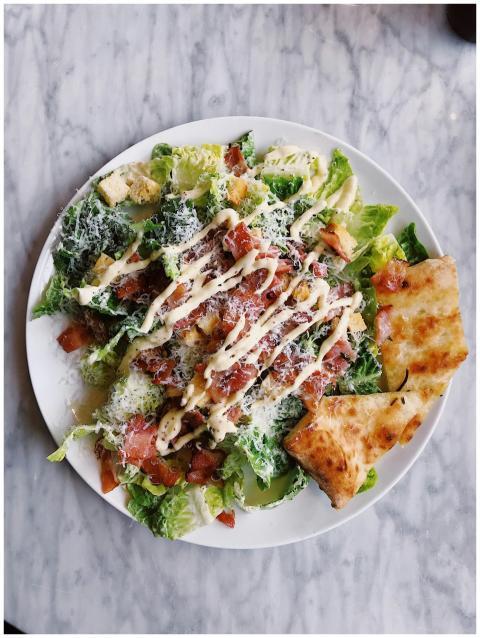 Tasty Caesar salad topped with bacon, cheese, and