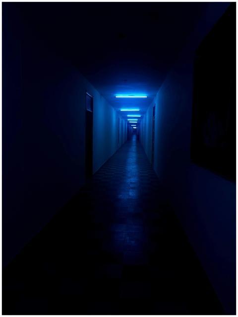A dark, narrow corridor illuminated by blue neon l