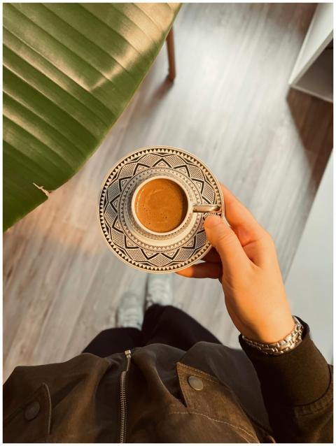 Person holding a patterned coffee cup indoors with