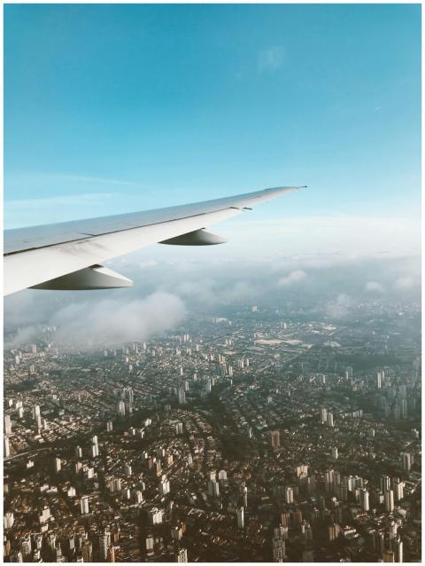 Airplane wing against a sprawling cityscape under