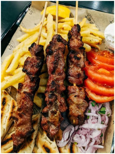Tasty grilled skewers served with fries, veggies,