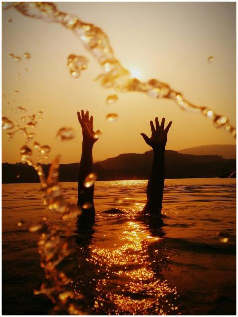 Silhouetted hands reach skyward in a golden sunset