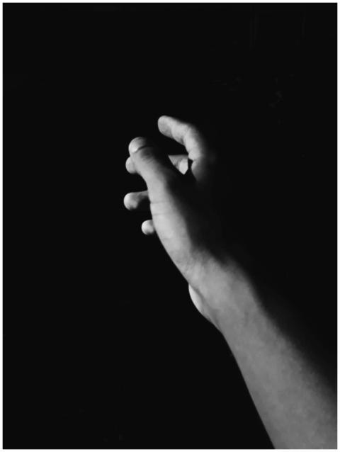 A solitary hand reaching out against a black backg