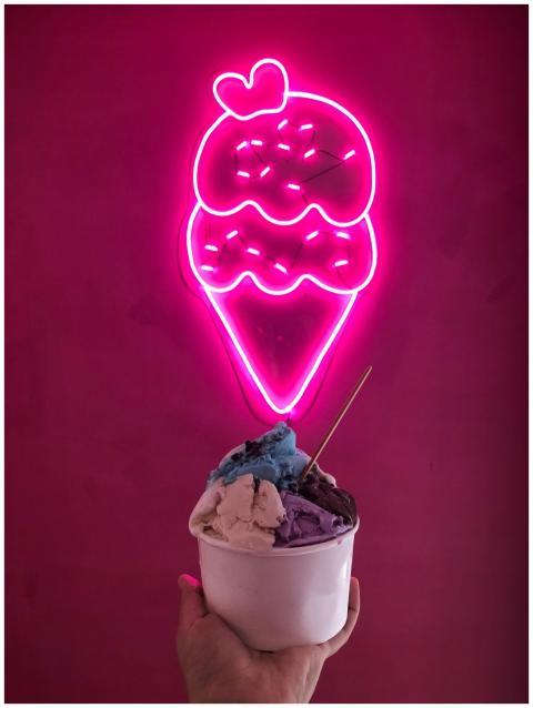 Multicolor ice cream in a cup below a neon ice cre