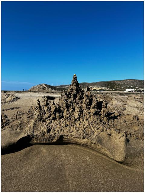 Intricate sandcastle under a clear blue sky on Gre