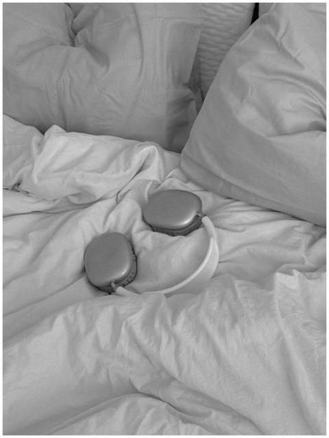 Stylish wireless headphones on a bed with pillows,