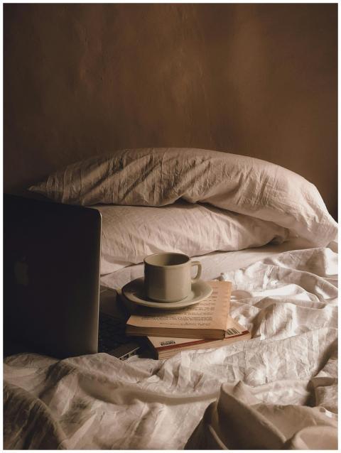 Relaxed bedroom setup with coffee, books, and a la