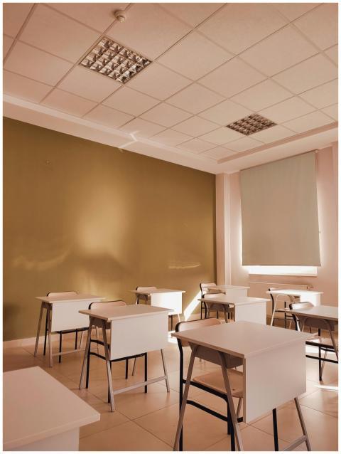 A minimalist classroom with arranged white desks a