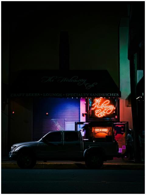 A neon-lit cafe on a city street at night with a t