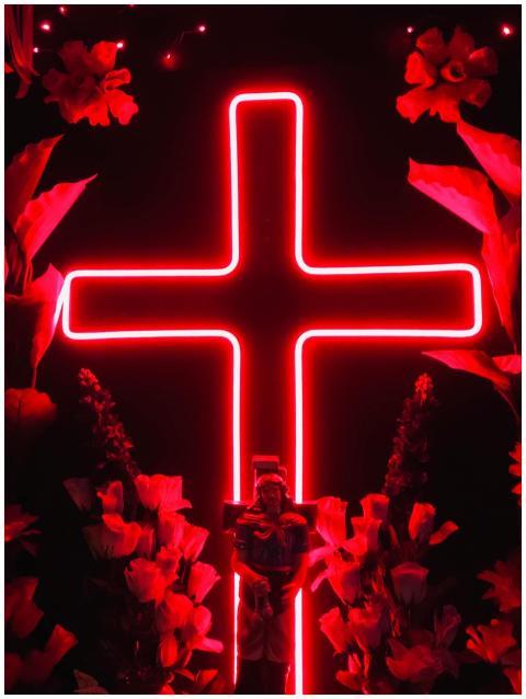 Vibrant red neon cross surrounded by glowing flowe
