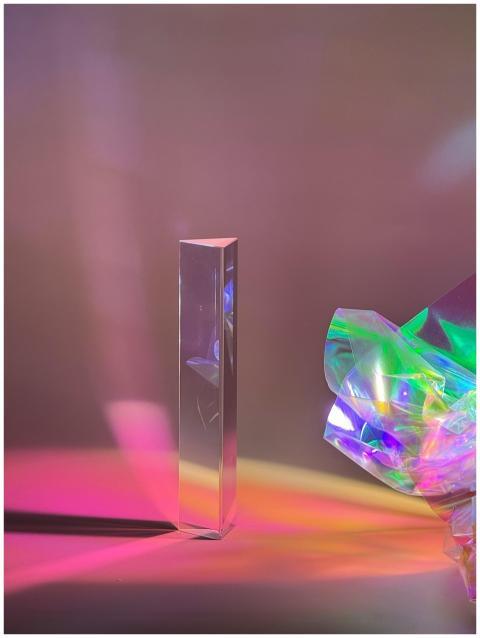 A tall prism casting colorful reflections on a sur