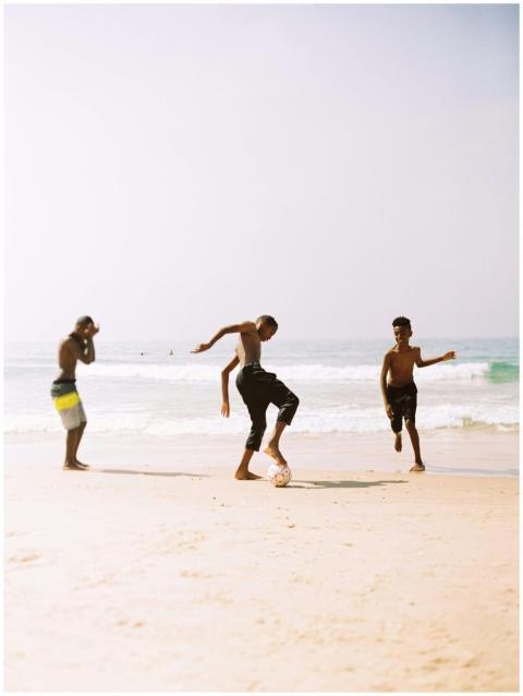 Three boys enjoying a game of soccer on a sunlit b