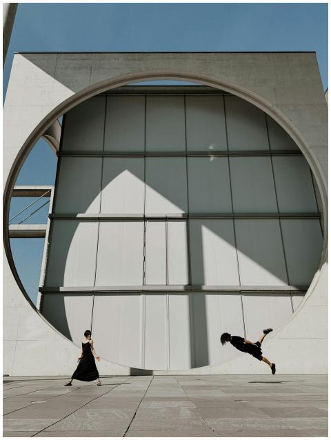 Silhouettes of two dancers pose dynamically agains
