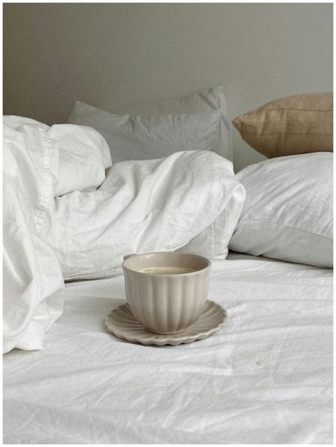 A calming scene of a coffee cup on a bed with pill