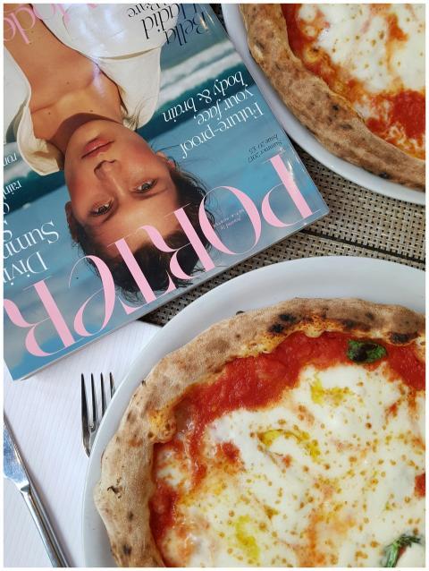 Close-up of a Margherita pizza with magazine on ta
