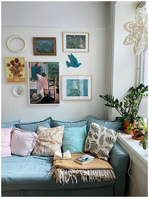 A cozy room with art, plants, cushions, and a wind