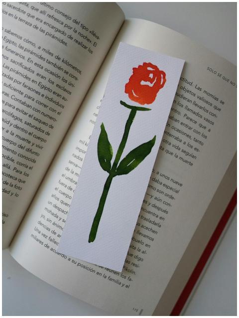 A handmade rose bookmark placed on an open book pa