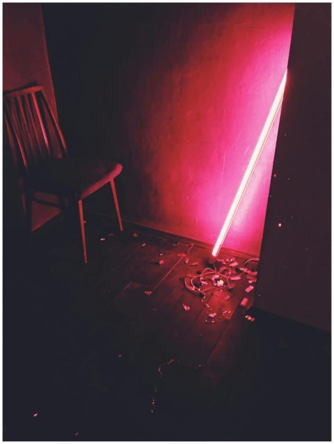 A dimly lit room with a neon glow casts a dramatic