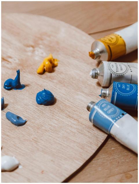 Multiple tubes of blue and yellow paint on a woode