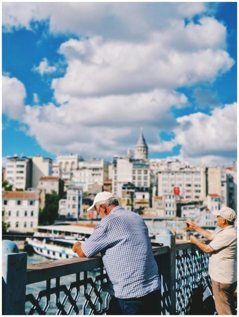 Two men fish from the Galata Bridge with the Galat