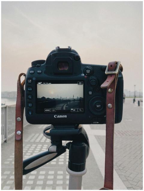 A DSLR camera on a tripod captures a scenic urban