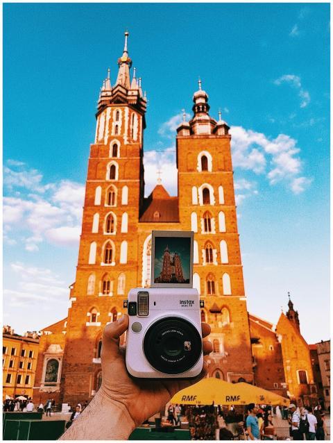 A hand holding a Polaroid camera captures St. Mary