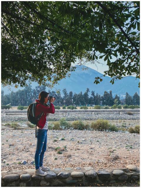 A woman captures a scenic outdoor view in Chile, f