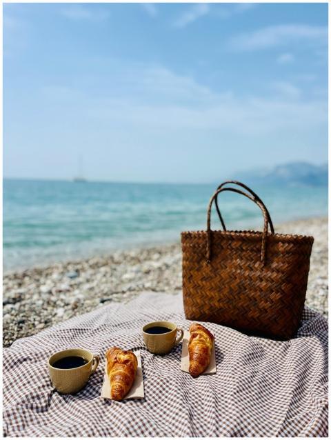A serene beach picnic setup with coffee, croissant