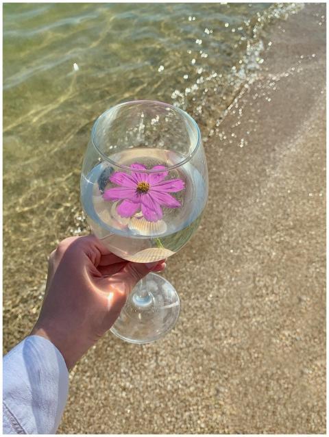 A wine glass with a floating flower held against a