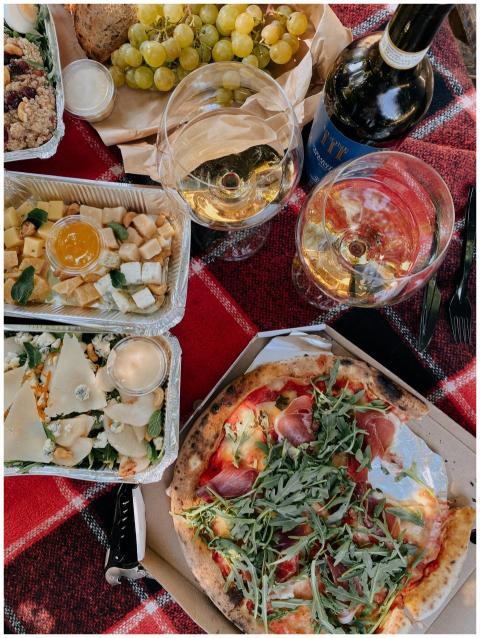 Flat lay of a gourmet picnic featuring wine, pizza