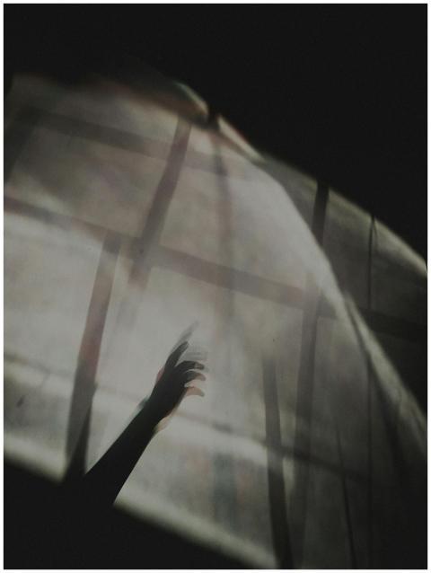 A shadow of a hand reaching through soft light dif