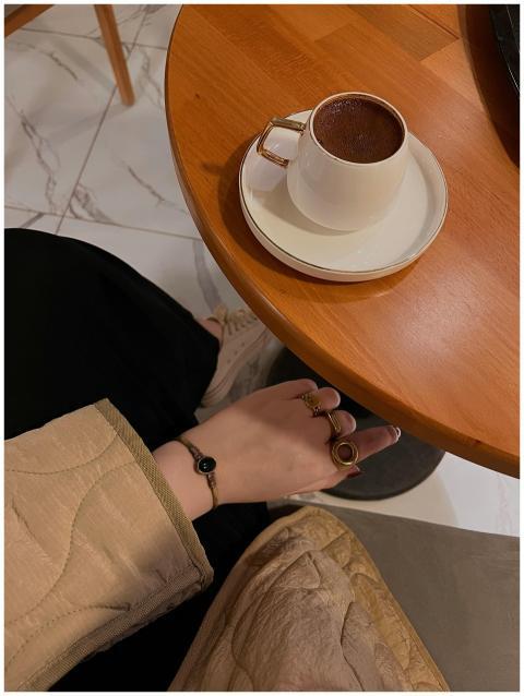 Hand with rings on a coffee table with a cup in a