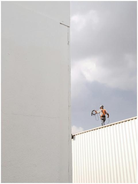 A construction worker stands on a rooftop against