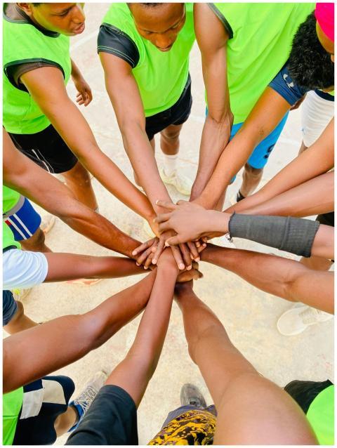 A diverse group of athletes join hands in unity du