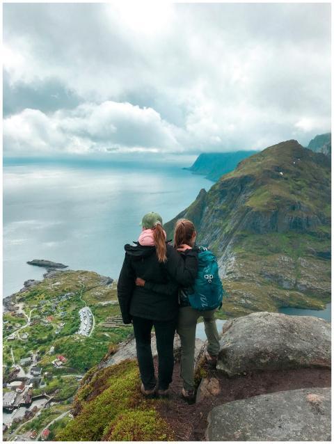 Two women hikers embracing atop a mountain with an