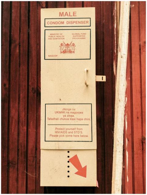 Condom dispenser on outdoor wooden wall promoting