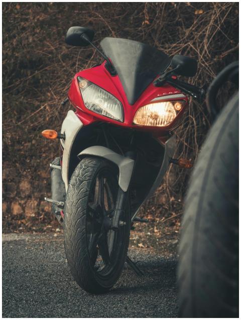 A striking red motorcycle parked on a secluded roa