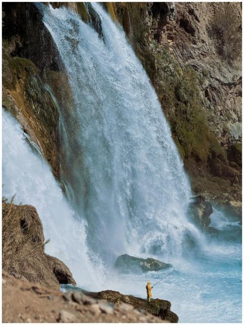 A powerful waterfall cascades down rocky cliffs wi