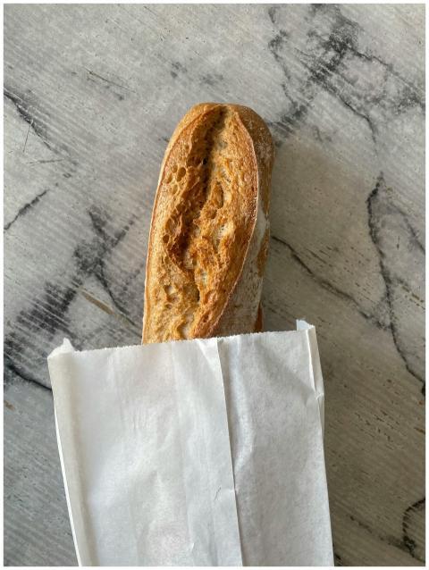 Crispy French baguette in a paper bag on a texture