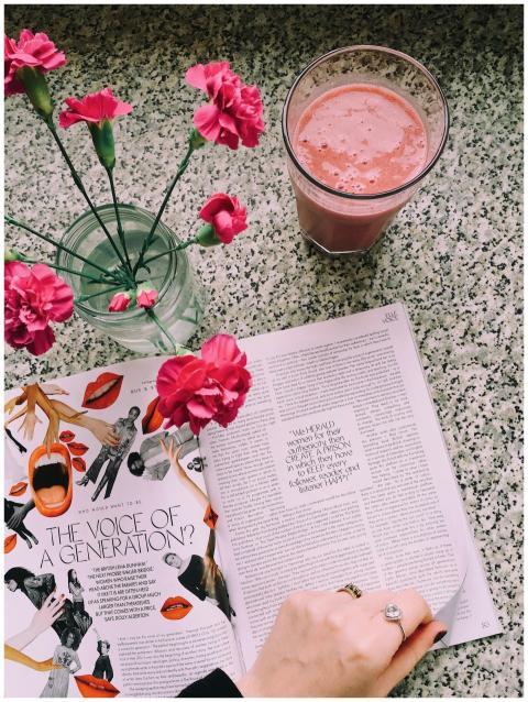 A fresh pink carnation vase, magazine, and smoothi